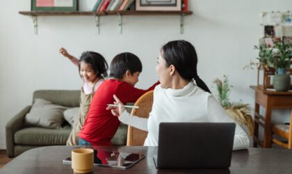 A lady handling two kids disturbing while working at home