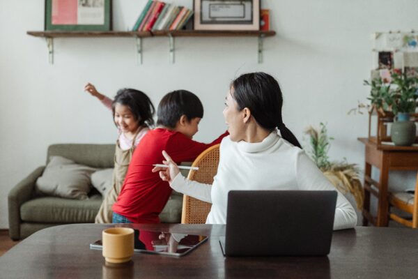 A lady handling two kids disturbing while working at home